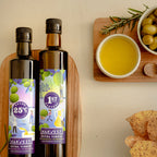 Two dark glass bottles of Harvest 1st Press extra virgin olive oil with purple and green labels, styled on a wooden board next to bowls of olives, a small bowl of yellow oil, crackers, and rosemary on a light beige background.