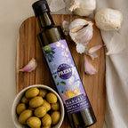 Adelaide Hills Harvest garlic infused extra virgin olive oil bottle with fresh garlic bulbs and green olives on wood