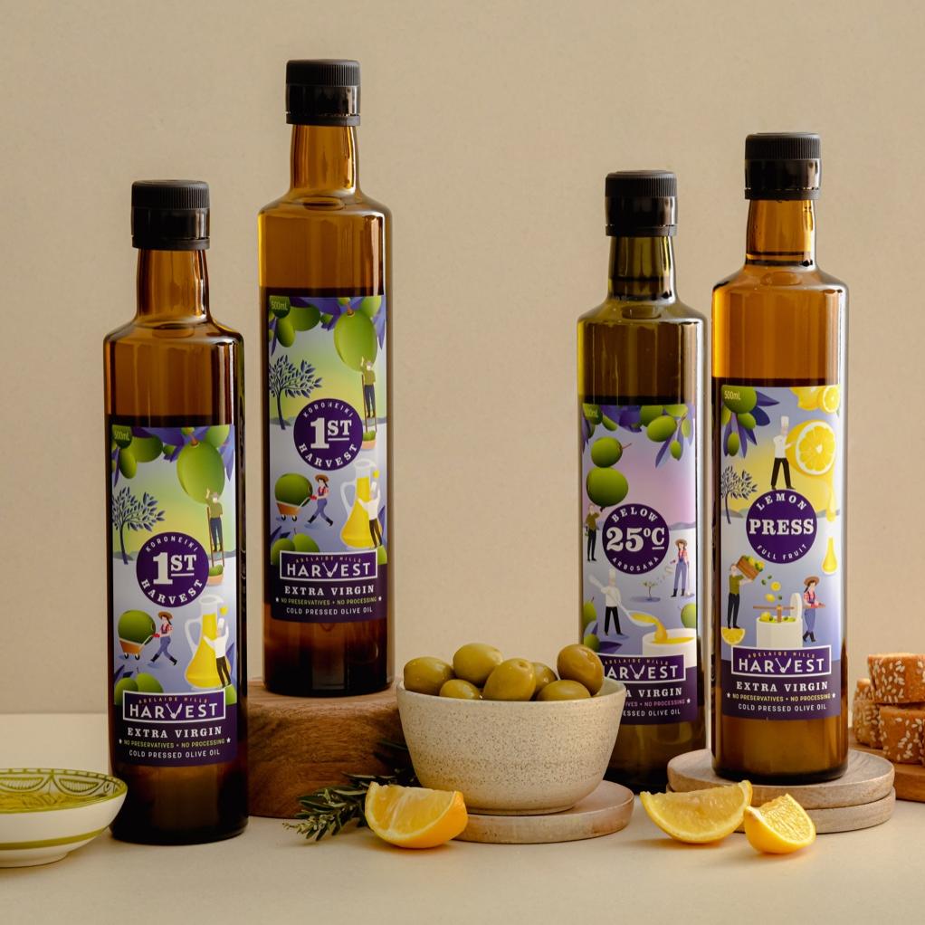 Adelaide Hills Harvest olive oil sample pack with four 500ml bottles, fresh lemons, and olives on a wooden surface.