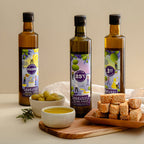 Adelaide Hills Harvest olive oil sample pack with three 500ml bottles, green olives, and sesame crackers on a board.